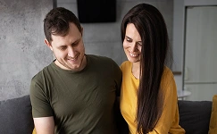 A man and a woman smiling and looking down together.